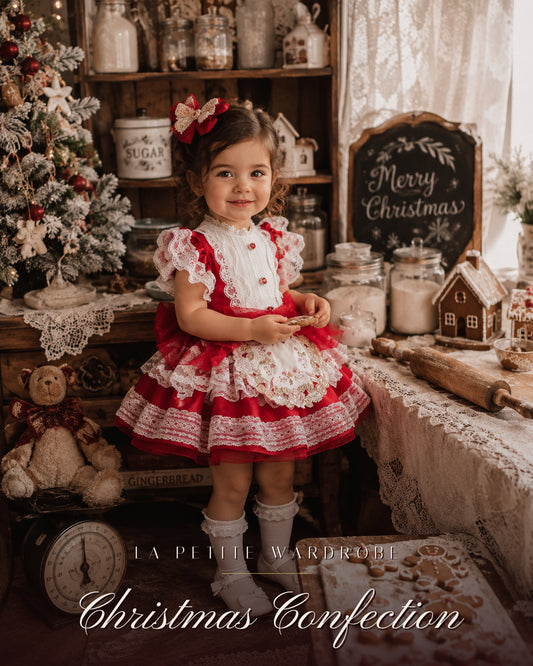 Girl wearing the Christmas Confection red taffeta dress with ivory lace trims and rose-embroidered apron